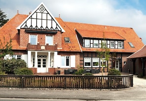 Il s’agit d’un bâtiment traditionnel, doté d’un toit à deux versants, d’une façade en briques et d’une clôture en bois à l’avant.