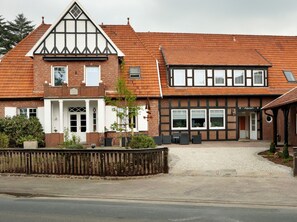 A traditional half-timbered building with a gabled roof, a front porch, and a gravel driveway. - Apartment "wheelhouse" - apartment / apartments (Lembruch)