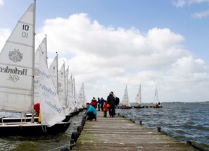 A row of sailboats docked at a pier with people standing on the pier. - Apartment "wheelhouse" - apartment / apartments (Lembruch)