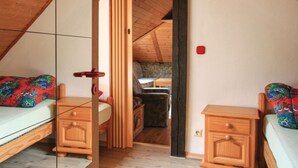 Ein gemütliches Schlafzimmer im Dachgeschoss mit schrägen Wänden, Holzmöbeln und einem kleinen Sofa.