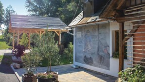 Ein Innenhof mit einer Holzpergola, Blumentöpfen und einem Wandgemälde.