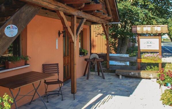 Un área de estar al aire libre con mesas y sillas de madera, una pérgola de madera y un letrero.