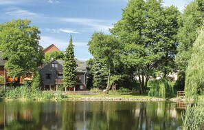 Un entorno tranquilo junto al lago, con una casa, un muelle de madera y abundante vegetación.