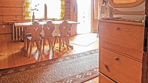 Un interno in legno con un tavolo da pranzo e sedie, un comò di legno e un tappeto decorato.