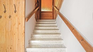 Una scala in legno con corrimano che conduce a una porta con un pannello di vetro smerigliato.