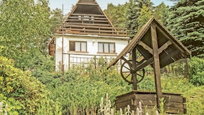 Una casa bianca con tetto a forma di triangolo e una struttura circolare in legno di fronte.