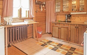 Eine rustikale Küche mit Holzschränken, einem Heizkörper und einer karierten Fußmatte.