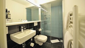 Une salle de bain moderne avec un lavabo blanc, des toilettes et une douche à parois de verre.