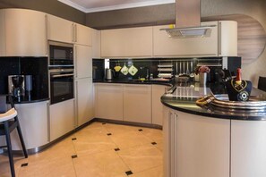 Une cuisine moderne dotée d’appareils électroménagers intégrés, d’un coin bar et d’un espace détente.