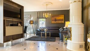 A modern living room with a flat-screen TV, a fireplace, a sofa, and a chandelier.