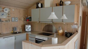 Cuina compacta amb armaris de fusta, rentaplats integrat, cafetera i un rentatègim.