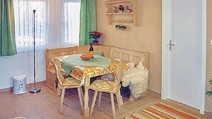 Comedor con una mesa, sillas, un cuenco de fruta, una botella y una planta.