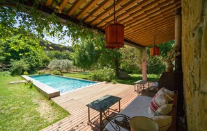 A wooden deck with a pool, outdoor furniture, and hanging lights. - Beautiful apartment in Alia PA (Alia PA)
