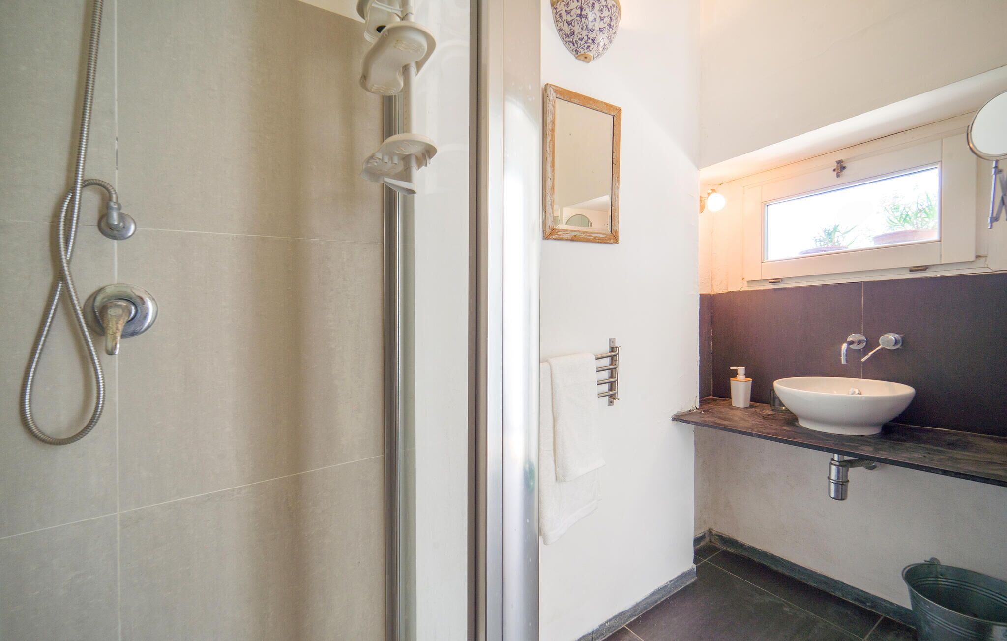 Un baño con ducha, lavabo, espejo y ventana.