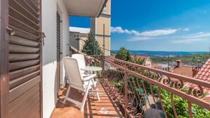 A balcony with a table and chairs, a view of the landscape, and a clock on the wall. - 3 bedroom awesome home in Praputnjak (Praputnjak)