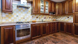 A kitchen with wooden cabinets, a gas stove, and a tiled backsplash. - 3 bedroom awesome home in Praputnjak (Praputnjak)