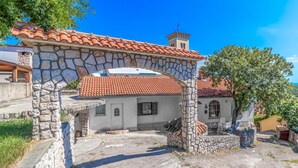 A stone archway leading to a building with a red-tiled roof and a small tower. - 3 bedroom awesome home in Praputnjak (Praputnjak)