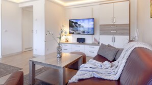 Una sala de estar moderna con un televisor de pantalla plana, un sofá, una mesa de centro y un mueble.