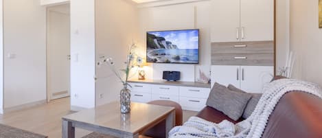 En moderne stue med et fladskærms-tv, en sofa, et sofabord og et skab.