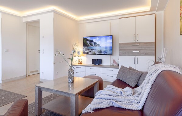 Un salon moderne comprenant un téléviseur à écran plat, un canapé, une table basse et un meuble.