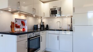 Una cocina moderna con armarios blancos, electrodomésticos de acero inoxidable y encimera negra.