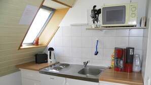 Une cuisine compacte équipée d’un évier, d’un four à micro-ondes, d’un grille-pain et d’une machine à café.