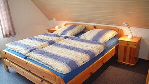 Un lit en bois recouvert d’une couvre-lit à rayures bleues et blanches, avec deux oreillers et deux tables de chevet dotées de lampes.