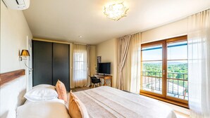 A hotel room with a bed, a desk with a TV, a chair, and a balcony with a view. - Pet friendly home in Jadrija with sauna (Jadrija)