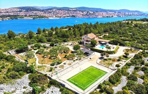 Escape to a serene retreat with a stunning city and sea view, surrounded by lush greenery and a tennis court.