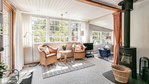 A cozy room with a fireplace, wicker chairs, a TV, and large windows. - 3 bedroom beautiful home in Nexø (Nexø)