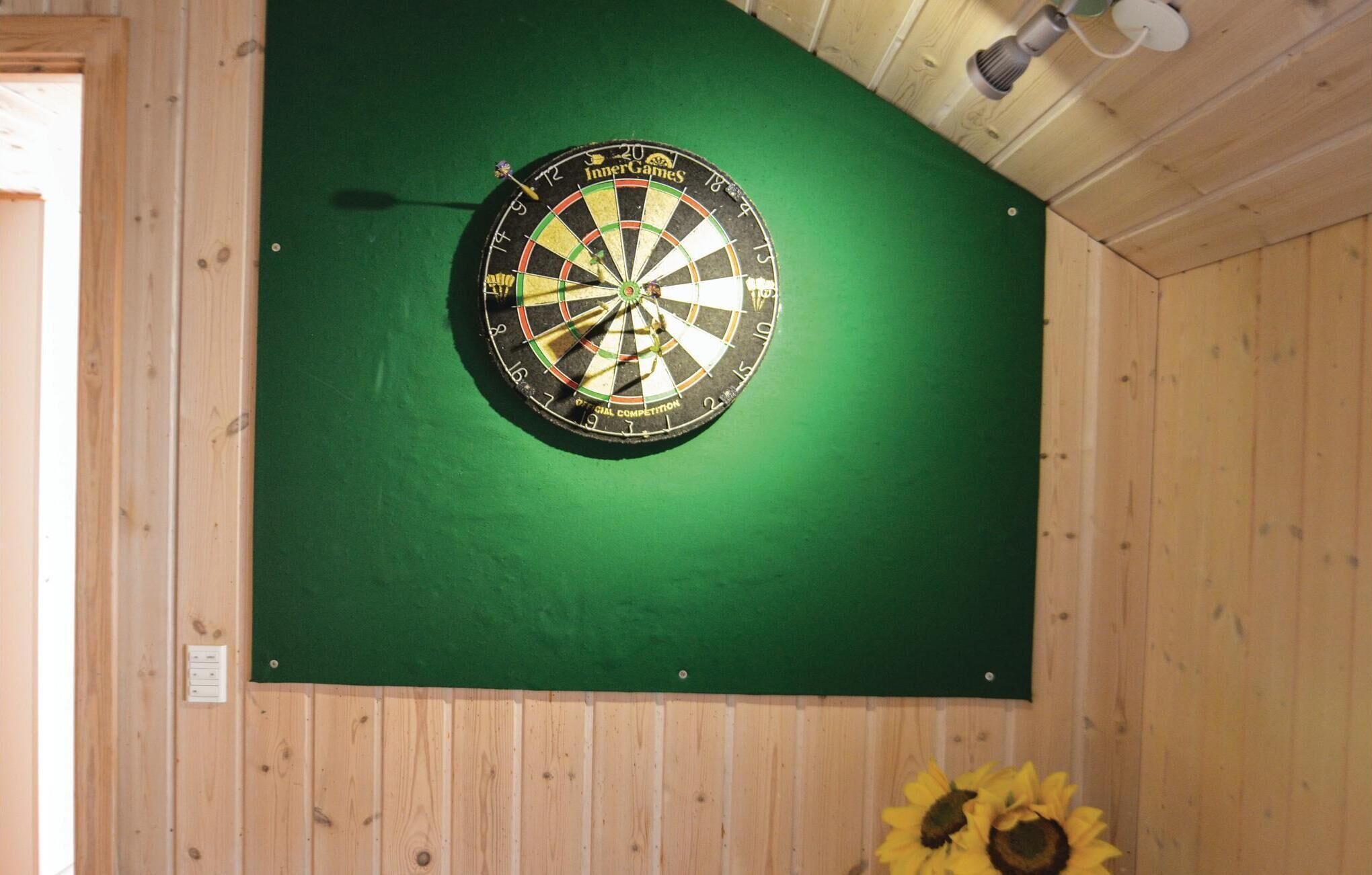 A dartboard mounted on a green wall in a wooden room.