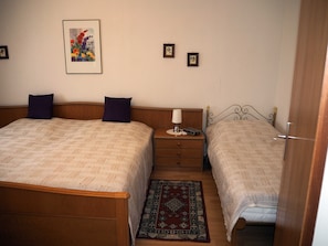 Un dormitorio con dos camas, una mesita de noche, una lámpara y un cuadro en la pared.