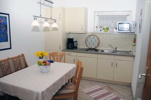 Una pequeña cocina con una mesa, sillas, microondas y un lavaplatos.
