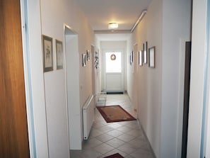 Un couloir avec un radiateur, une porte et un tapis.