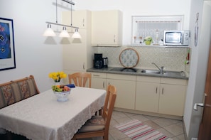 Una pequeña cocina con una mesa, sillas, microondas y un lavaplatos.