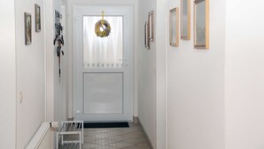 A hallway with a white door, a wreath, and framed pictures on the walls. - Vacation apartment Niewand (Clausthal-Zellerfeld)