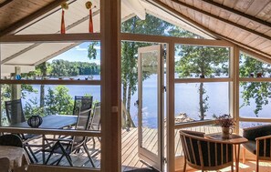 A wooden deck with a table and chairs, overlooking a lake with trees and a dock. - Awesome home in Lidhult with sauna (Lidhult)