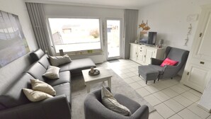 Un salon avec un canapé, un fauteuil et un téléviseur posé sur un meuble.