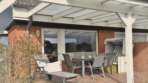 Une terrasse avec une table et des chaises, un espace abrité et un mur en briques.