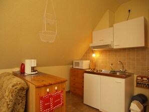 Eine kleine Küche mit Holzarbeitsplatte, einer Mikrowelle, einem Spülbecken und einem kleinen Kühlschrank.