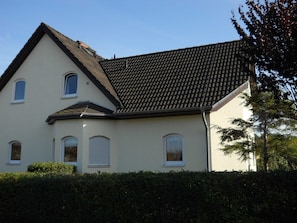 A two-story house with a sloped roof, multiple windows, and a white exterior.