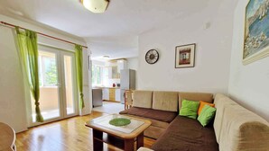 A spacious living room with a sofa, a coffee table, and a view of the kitchen. - Holiday flat with air conditioning and terrace (Baška)
