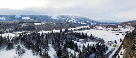 A snow-covered landscape with a road and buildings in the distance.