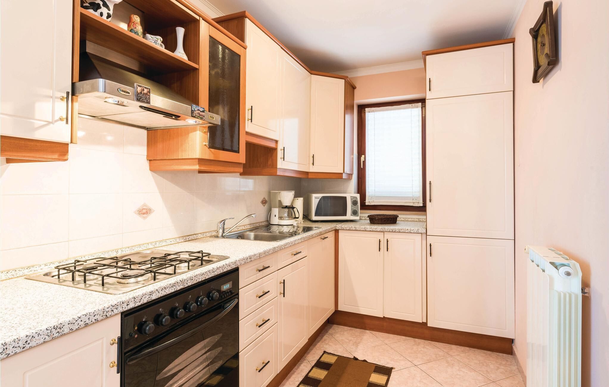 A kitchen with a gas stove, oven, microwave, and a window.