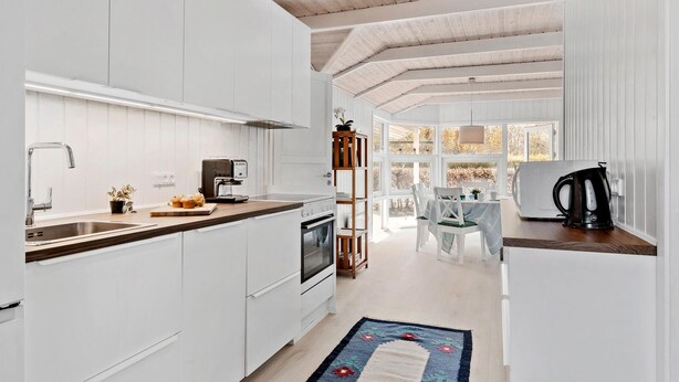 Una cocina moderna con armarios blancos, una cafetera y un comedor con mesa y sillas.