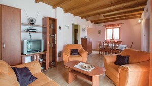 Ein gemütliches Wohnzimmer mit Holzmöbeln, einem Fernseher und einem Essbereich mit Tisch und Stühlen.