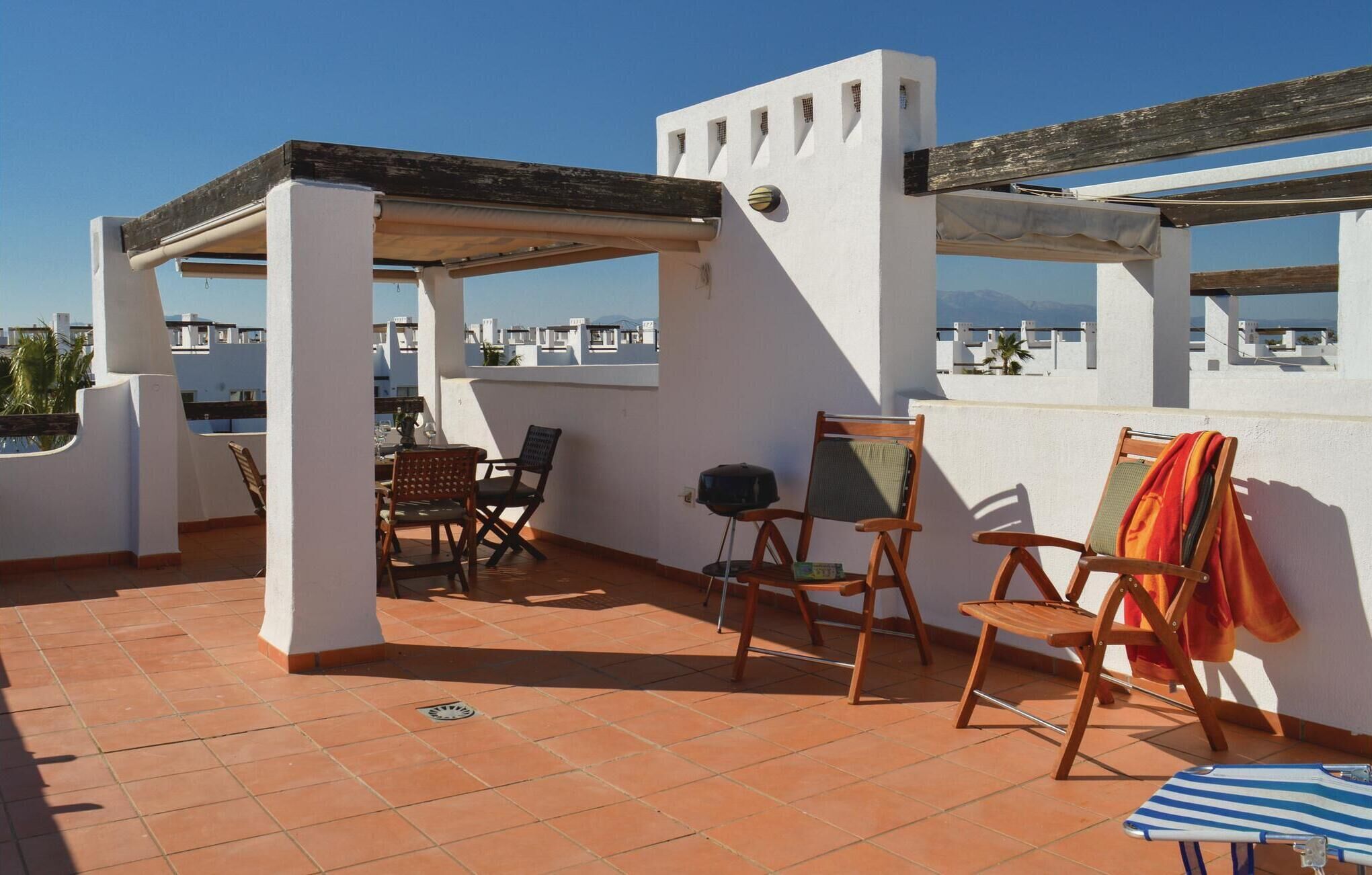 Eine Dachterrasse mit einer Pergola, einer Sitzgelegenheit und Blick auf die Stadtlandschaft.
