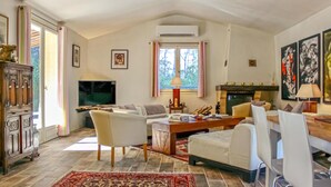 Un salón amplio con chimenea, televisor y un ventanal con cortinas.