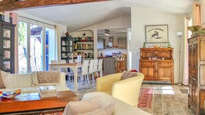Una sala de estar con sofá, una mesa de centro y un comedor con sillas y mesa. Se observa una zona de cocina con armarios y una mesa para comer.