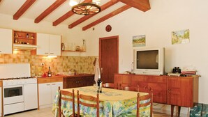A kitchen with a dining area, wooden beams, a stove, cabinets, and a television. - 2 bedroom awesome home in Teyssieres (Teyssieres)